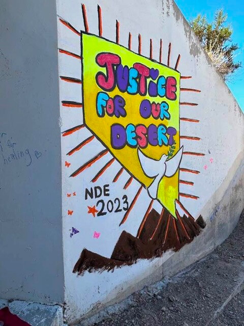 A painted mural on a concrete wall reading "Justice For Our Desert," Nevada Desert Experience, 2023.